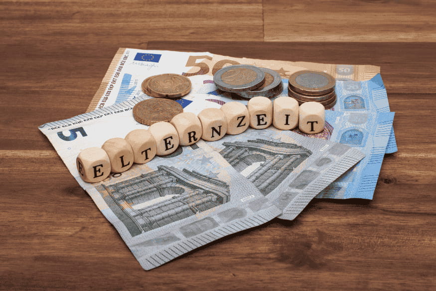 Euro-Scheine und Münzen mit Holzbuchstaben, die das Wort Elternzeit bilden