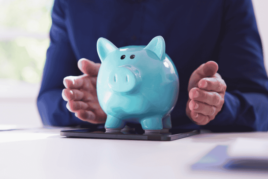 Hände schützen blaues Sparschwein als Symbol für gemeinsame Rücklagen in der Patchworkfamilie