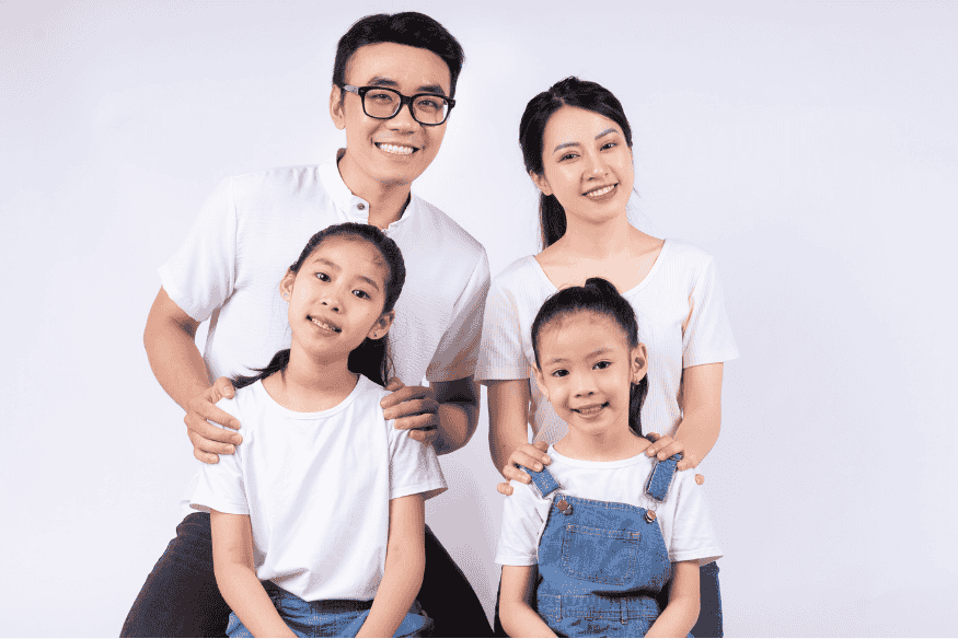 Lachende Patchworkfamilie mit Eltern und zwei Kindern vor hellem Hintergrund