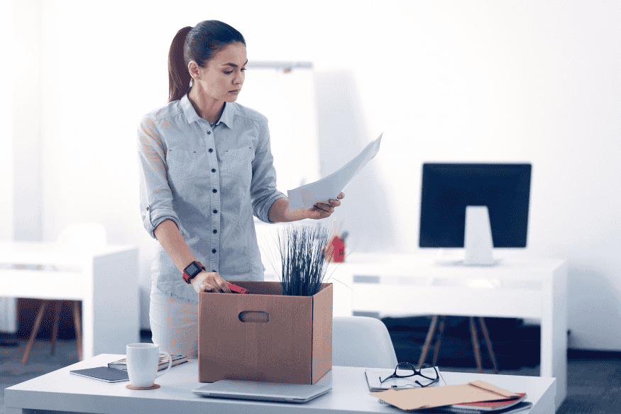 Frau packt nach Jobverlust ihre Sachen im Büro und bereitet finanziellen Notfallplan vor