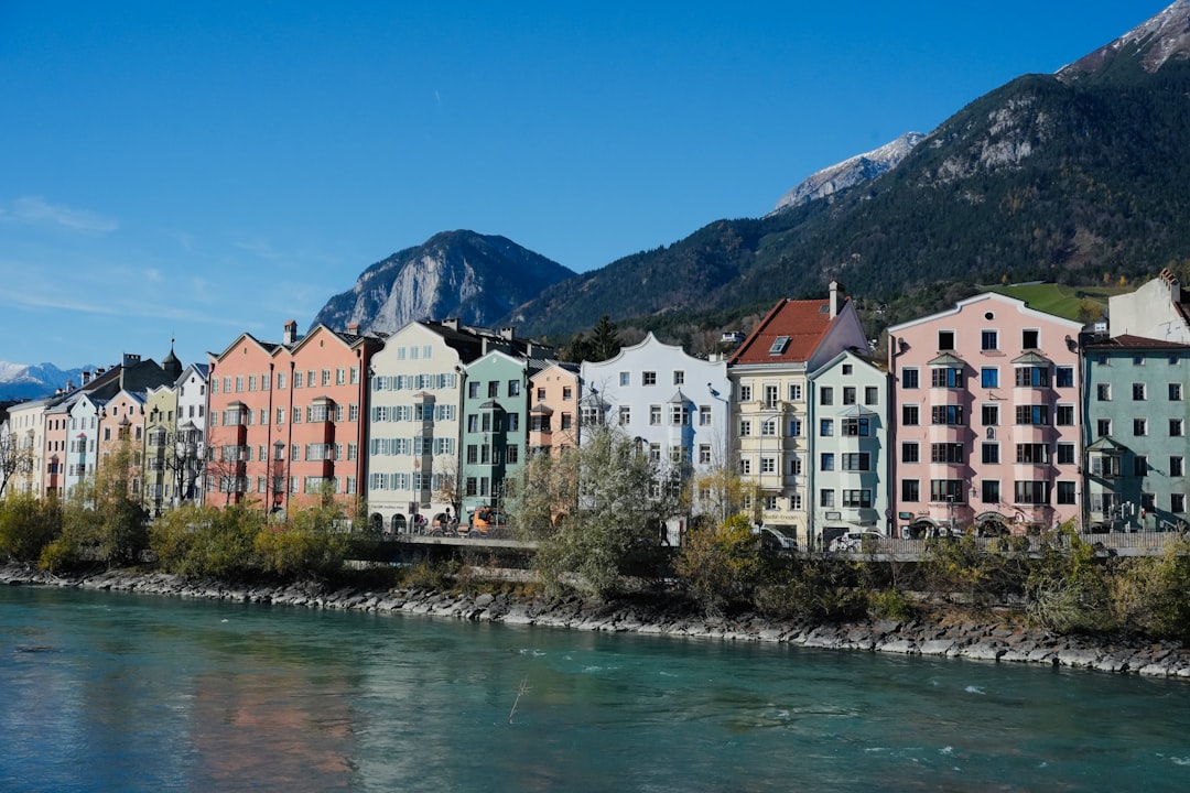 Colorful buildings line a river with mountains behind.