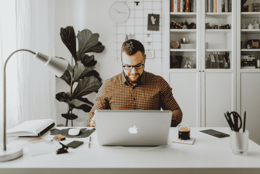 Mann arbeitet im Homeoffice am Laptop und plant sein Nebeneinkommen als Freelancer