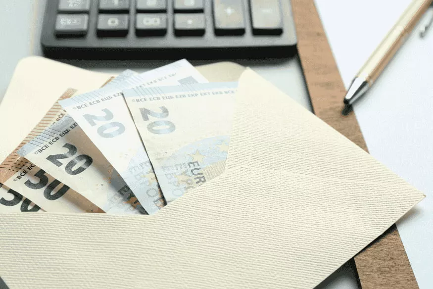 Euro-Scheine im Briefumschlag neben Taschenrechner als Symbol für versteuertes Nebeneinkommen