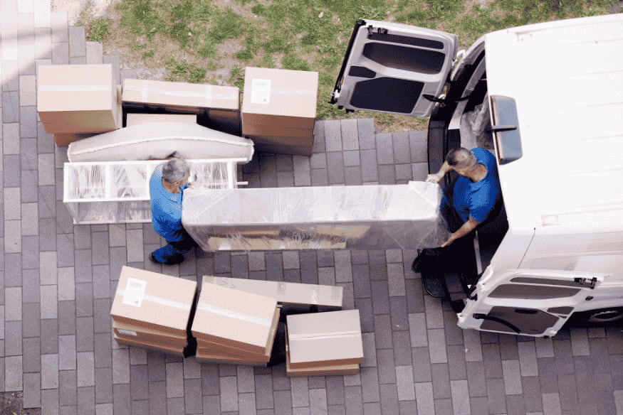 Umzugshelfer laden Möbel und Umzugskartons aus Transporter, um Umzugskosten und Organisation zu planen