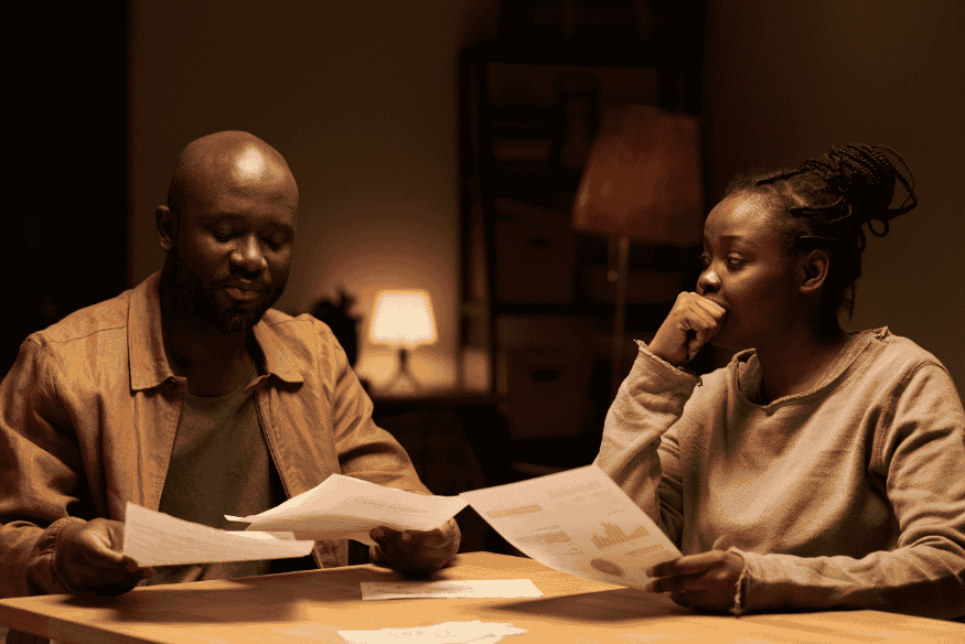 Paar prüft abends Unterlagen und rechnet Mietkaution, Doppel-Miete und Umzugskosten durch