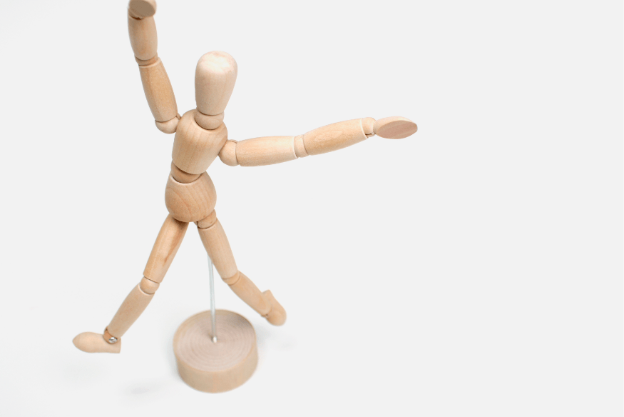 Holzfigur in dynamischer Pose auf hellem Hintergrund – symbolisiert die Flexibilität und Anpassungsfähigkeit finanzieller Mikroziele bei sich verändernden Lebenssituationen.