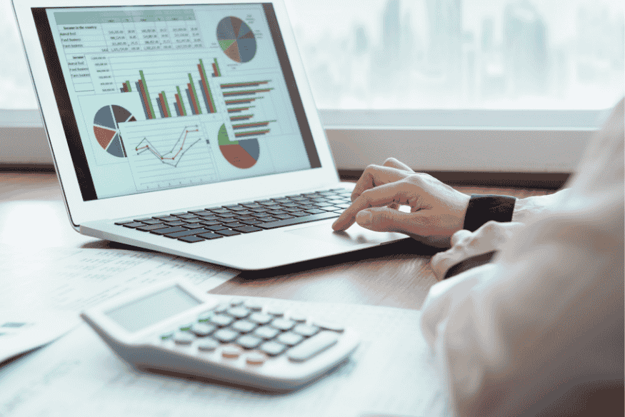 Person arbeitet mit Finanzübersicht und Diagrammen am Laptop, daneben ein Taschenrechner – steht für die Auswertung und Kontrolle von Ausgaben im Sinne des finanziellen Minimalismus.