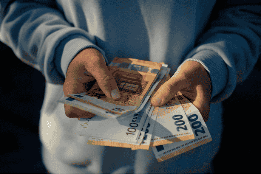 Person hält mehrere Euro-Scheine in der Hand als Zusatzeinkommen aus Nebenjob