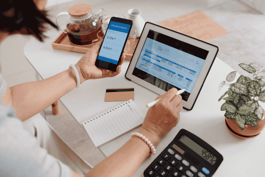 Person vergleicht Kontostand per Online-Banking auf Smartphone und Tablet, um Steuerersparnis zu berechnen