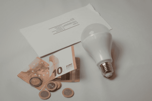 LED-Lampe, Euro-Scheine und Stromrechnung als Symbol für niedrigere Stromkosten