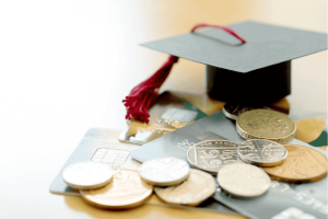 Absolventenhut auf Kreditkarten und Münzen als Symbol für Studienkosten und Schuldenfalle