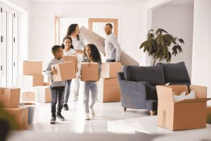 Familie trägt Umzugskartons in neues Zuhause und plant Budget für Miete und Kaution